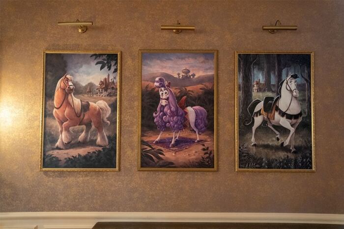 Trois tableaux de chevaux accrochés sur un mur de l'hôtel Disneyland.