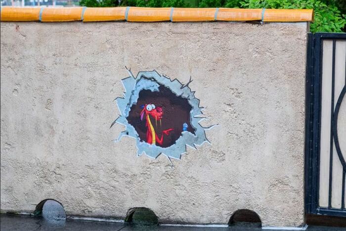 Un trou dans le côté d’un mur avec une image d’un chien dessinée à la craie.